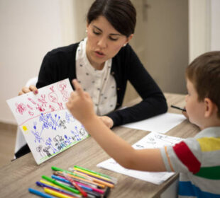 Five years old boy drawing at the psychotherapy session.